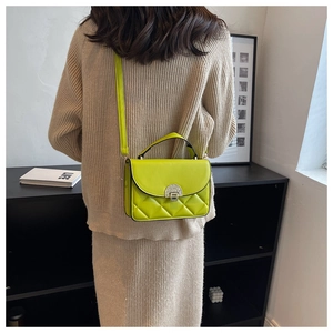 Detail view of neon yellow quilted handbag with unique semi-circular metal lock