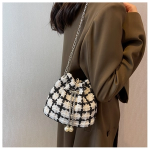 Detailed view of checkered tweed bucket bag with elegant large pearl drawstring charms