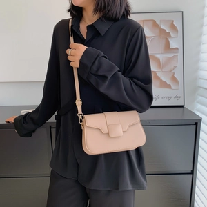 Minimalist beige leather crossbody square bag with adjustable strap worn by model