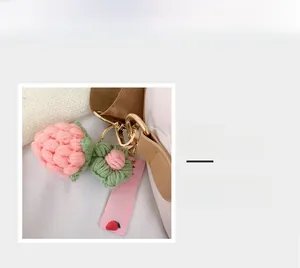 Nahaufnahme eines gestrickten Erdbeeren- und Blumenanhängers mit goldenem Metallhaken