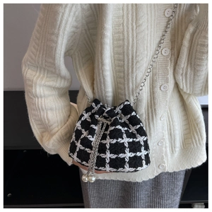 Detail of black and white woven bucket bag with pearl drawstring and silver chain strap