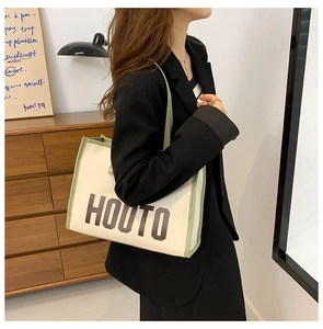 Détail du cabas en toile avec bordure verte contrastée et inscription HOUTO élégante