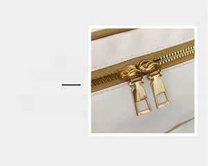 Detailaufnahme glatter goldener Doppelreißverschlüsse an einer weißen Lederhandtasche