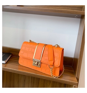 Detailansicht: Orangefarbenes Leder mit Krokoprägung, goldener Schnalle und Metallkette