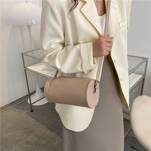Minimalist beige cylinder shoulder bag in smooth leather with adjustable strap for women