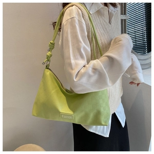 Detail of light green faux leather shoulder bag with checkerboard embossing and knot strap