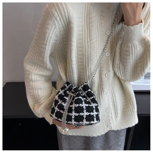 Detail of tweed checkered bucket bag with silver chain strap and large pearl charms