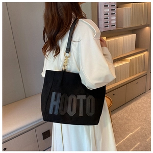 Detail view of black tote bag with HOOTO lettering and gold ring hardware accents