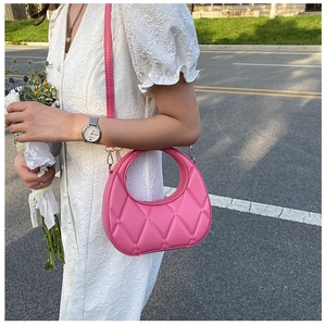 Detail of pink half-moon bag featuring quilted stitching and hollow circular handle