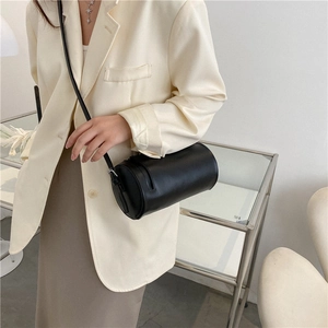 Minimalist black leather barrel bag styled with a beige blazer for a modern fashion look