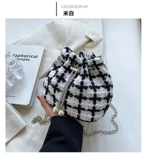 Detail of tweed bucket bag with metal chain strap and pearl drawstring in cream and black