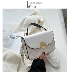 Close-up of white quilted crossbody bag with gold lock and black top handle detail