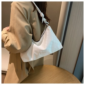 Close-up of white minimalist hobo bag with quilted texture and knot detail on the strap