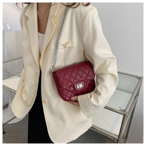 Detail of burgundy quilted crossbody bag with silver chain strap and metal lock