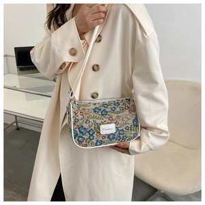 Close-up of vintage floral embroidery and fashion label on a white crossbody bag