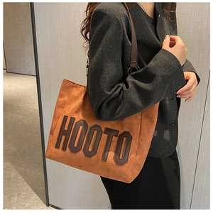 Close-up of orange suede tote bag with brown HOOTO lettering and slim shoulder straps