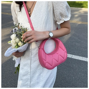 Detail of pink quilted dumpling bag with circular cutout handle and silver metal hardware