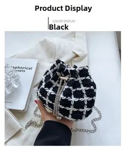 Detail of black and white checkered knit bucket bag with pearl chain strap on desk