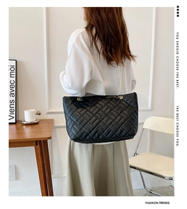 Vista dettagliata della grande borsa tote nera trapuntata con catena metallica dorata su modella