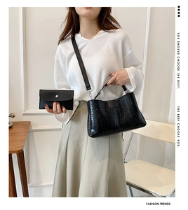 Gros plan du sac à main noir à motif crocodile avec son petit porte-monnaie assorti