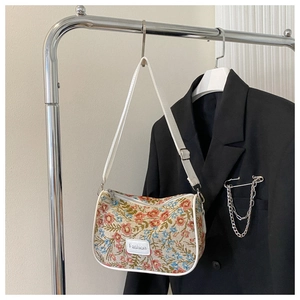Detail of floral tapestry fabric and white leather trim on retro shoulder bag