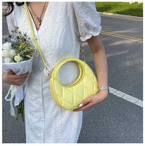Close-up of bright yellow crescent bag with quilted leather texture and shoulder strap