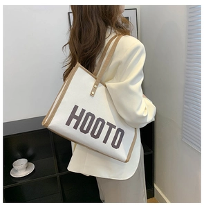 Photo lifestyle d'un grand sac cabas en toile avec bordure en cuir brun et texte HOOTO