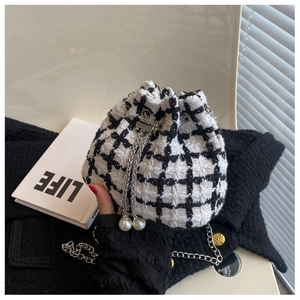 Close-up of houndstooth tweed bucket bag with pearl charm and metal chain strap