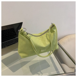 Detail of light green shoulder bag featuring checkerboard texture and knotted strap detail
