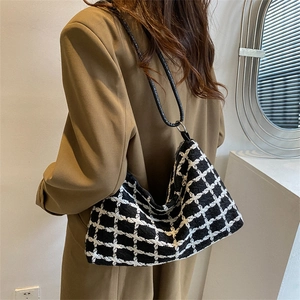 Elegant black and white plaid tweed hobo shoulder bag shown on a model in a minimalist setting