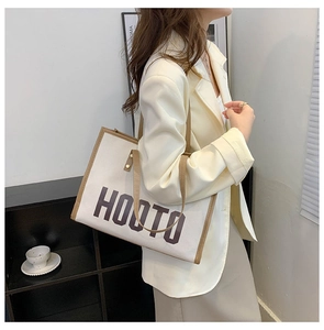 Détail du sac cabas en toile avec logo HOOTO et finitions en cuir marron de haute qualité
