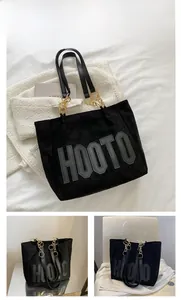 Detail showing black suede tote bag with HOOTO letter print and gold chain strap