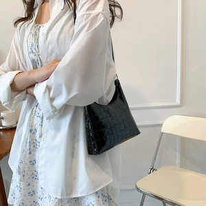 Fashionable black crocodile pattern underarm tote bag for women in a modern urban setting