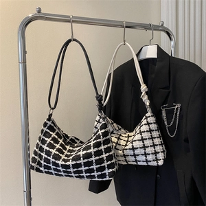 Classic checkered tweed shoulder bags in black and white hanging on a minimalist rack