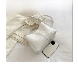 Détail du sac cabas blanc motif crocodile avec un smartphone pour comparer la taille
