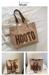 Detail view of khaki suede tote bag with leather HOOTO logo and gold chain strap