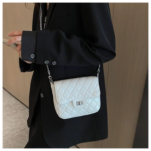 Detail of white quilted crossbody bag with silver chain strap and twist-lock on a model