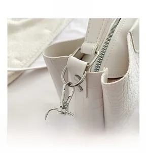 Détail du sac blanc motif crocodile avec fermoir mousqueton argenté et anneau en D