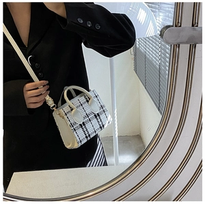 Détail du sac à main élégant en tweed à carreaux noir et blanc avec anses en cuir blanc