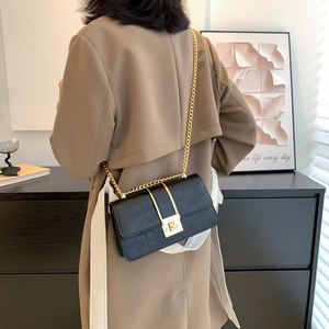 Minimalistische schwarze Kroko-Umhängetasche mit goldener Kette am Modell