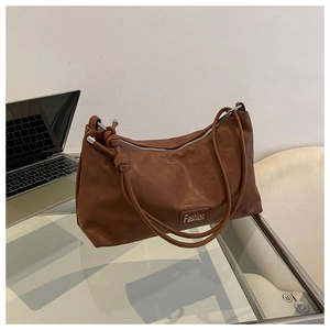 Detailed view of brown woven texture bag with knotted shoulder strap and silver zipper