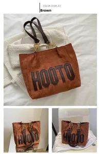 Detail of brown tote bag with HOOTO lettering and gold chain strap attachment
