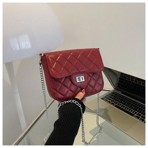 Macro detail of red quilted leather handbag with silver chain strap and metal turn-lock