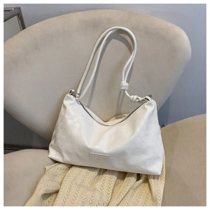 Detail of white woven shoulder bag featuring textured pattern and Fashion label decoration