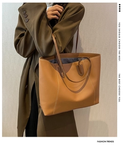 Large brown tote bag with contrast stitching detail and long shoulder straps worn by model