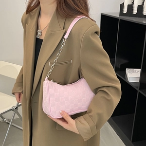 Pink checkered plush underarm bag with silver chain strap shown on model's shoulder