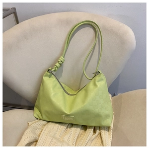 Detail of neon green checkered handbag with knotted strap on a textured soft chair