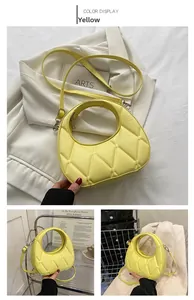 Detail view of yellow quilted dumpling bag with round cutout handle and slim strap