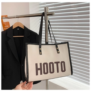 Détail du sac fourre-tout en toile crème avec bordure noire et imprimé HOOTO