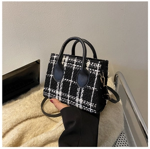 Détail du sac bandoulière en tweed noir et blanc avec poignées en cuir et boucles dorées